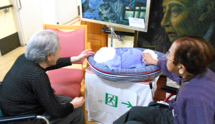 コミュニケーションロボットの『パロちゃん』に集まる利用者さんたち